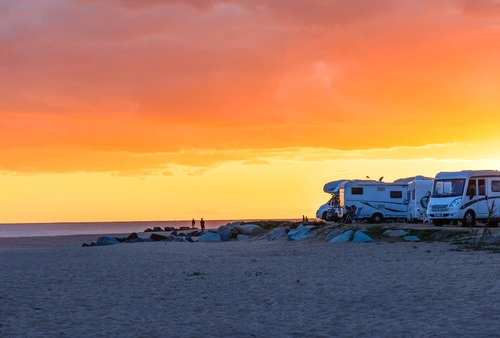 RVs parked on a beach at sunset