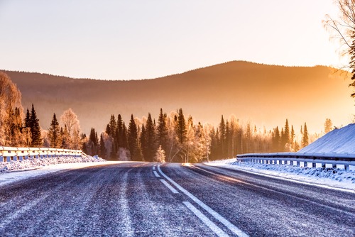 snowy roads overlooking tree covered hills at sunset
