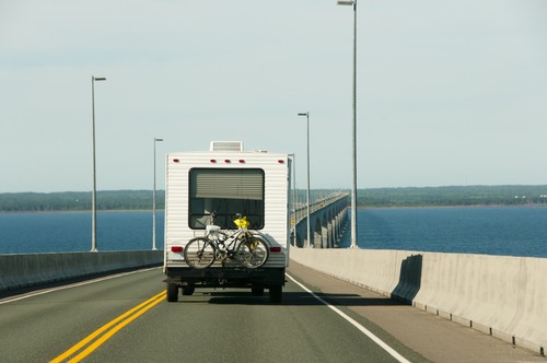 RV with bikes on a rack driving over a bridge