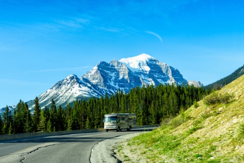 RV driving on a road with a mountain in the background