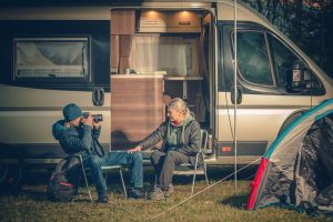 couple sit by RV trailer