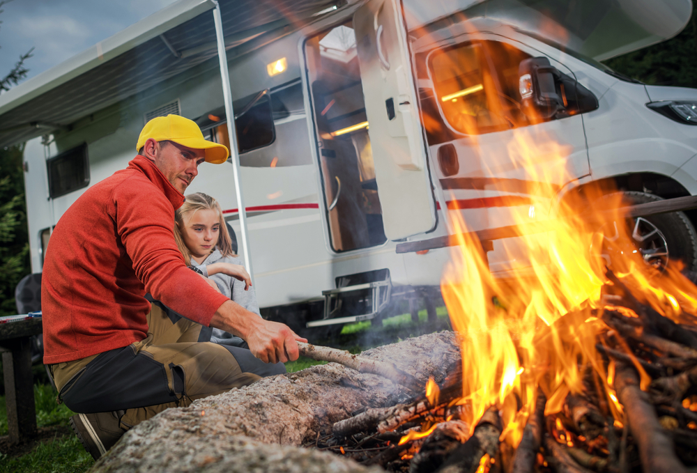 family with campfire and RV