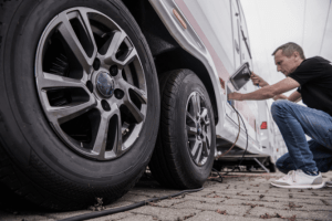 RV Tires and a man checking his RV exterior.